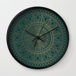 Pu&ograve; includere: Un orologio da parete blu turchese con un design a mandala dorato. L'orologio ha lancette nere e una cornice nera.