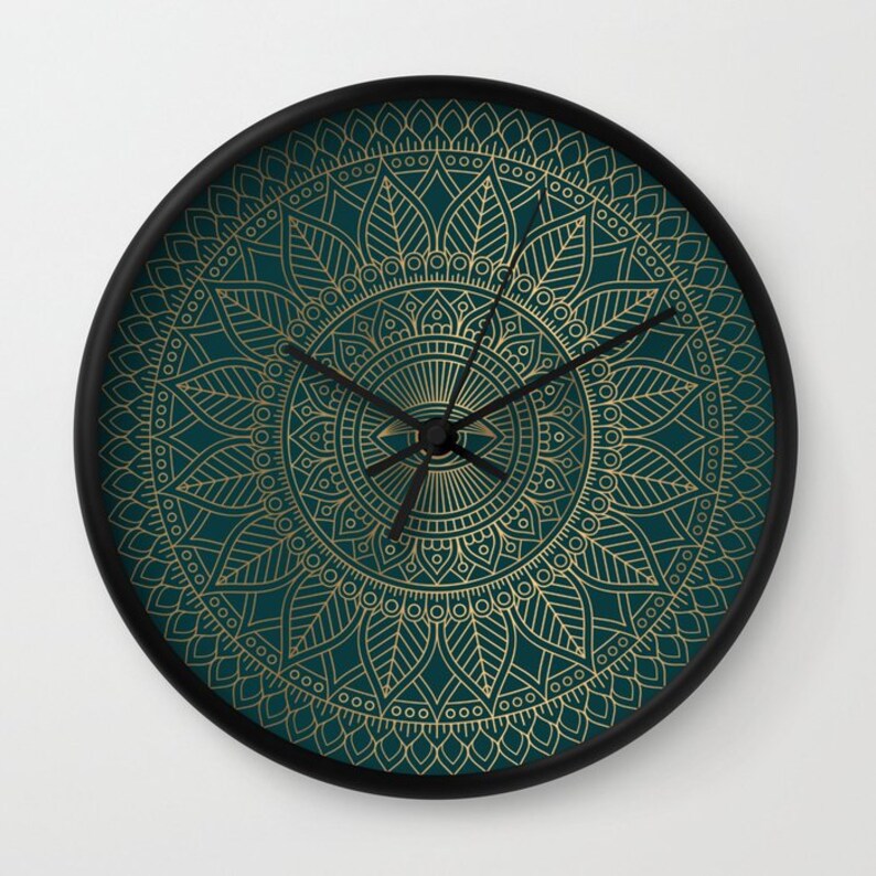 Pu&ograve; includere: Un orologio da parete blu turchese con un design a mandala dorato. L'orologio ha lancette nere e una cornice nera.
