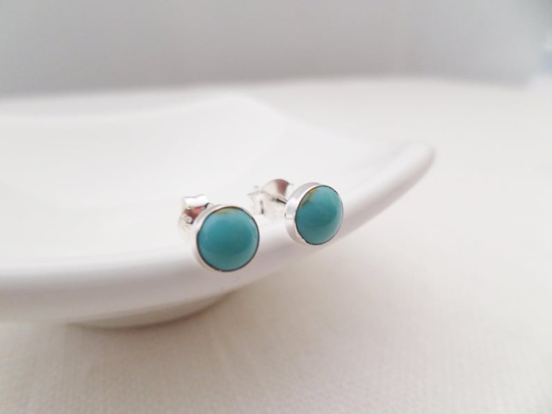 May include: A pair of silver stud earrings with turquoise stones.