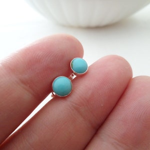 May include: A pair of silver stud earrings with turquoise stones. The earrings are small and round.
