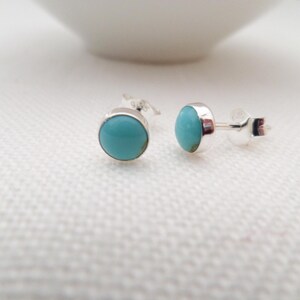 May include: A pair of silver stud earrings with turquoise stones.