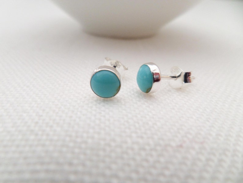 May include: A pair of silver stud earrings with turquoise stones.