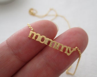 Puede incluir: Collar de oro con la palabra "mamá" escrita en letras mayúsculas.