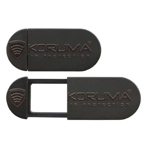 Puede incluir: Una cubierta de cámara web negra con un mecanismo deslizante. La cubierta tiene el texto "KORUMA® ID PROTECTION".