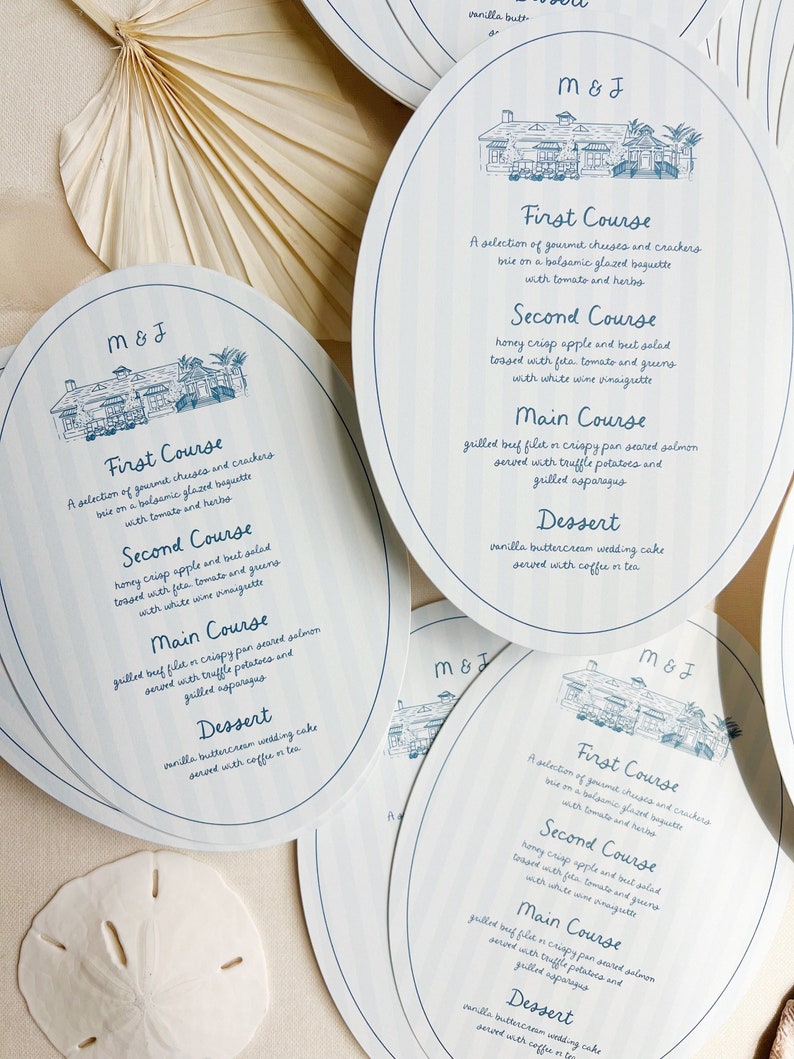 May include: Blue and white oval-shaped wedding menu cards with a hand-drawn illustration of a building with trees. The menu includes the text "M&J" and lists the courses: First Course, Second Course, Main Course, and Dessert.
