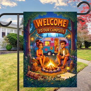 May include: A rectangular garden flag featuring a colorful illustration of two people sitting by a campfire in front of a vintage camper. The text reads WELCOME TO OUR CAMPSITE and The McCanns. The scene includes trees, lanterns, and camping gear.