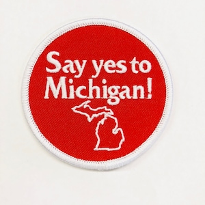 May include: Red round embroidered patch with white stitching. The patch says "Say yes to Michigan!" with an outline of the state of Michigan in white.