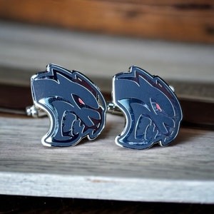 May include: A pair of silver cufflinks featuring a black and red 3D image of a snarling animal head.