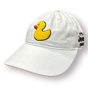 May include: White baseball cap with a yellow rubber ducky embroidered on the front. The text "It's a Jeep Thing" is embroidered on the side of the cap.