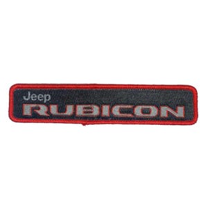 Puede incluir: Un parche bordado rojo y negro con el texto "Jeep RUBICON" en letras plateadas.