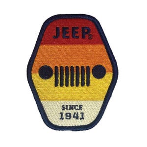 Może przedstawiać: Haftowana naszywka z logo Jeep i napisem "Since 1941". Naszywka ma retro design z poziomymi paskami w kolorach czerwonym, pomarańczowym, żółtym i kremowym. Logo Jeep zawiera kultowy wzór grilla.