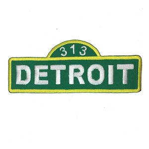 May include: Green and yellow embroidered patch with the text "DETROIT" and the number "313" above it.