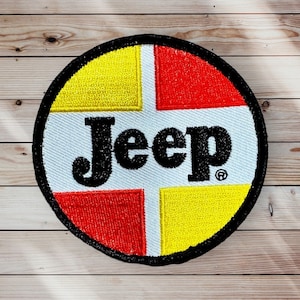 May include: A round, black-bordered patch with a white background and the word "Jeep" in black letters. The background is divided into four sections, two yellow and two red.