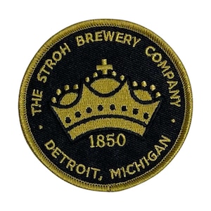 May include: Circular black patch with gold embroidered text and a gold crown design. The text reads "THE STROH BREWERY COMPANY DETROIT, MICHIGAN 1850". The patch has a gold border.
