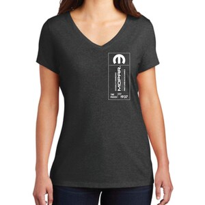 Puede incluir: Camiseta de cuello en V gris oscuro con un logotipo blanco en el pecho. El logotipo presenta el logotipo de Mopar y el texto "Mopar Parts and Accessories" y "Time Proven 1937".