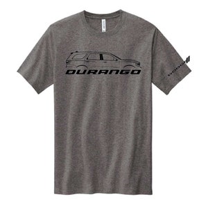 May include: A grey t-shirt with a black outline of a Durango SUV and the name "DURANGO" in bold, black letters. The Dodge logo is printed on the sleeve. The shirt is made of a soft material.