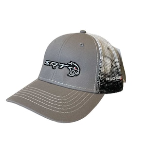 Puede incluir: Gorra de béisbol gris con costuras blancas y una parte trasera de malla. La gorra presenta el texto "SRT" en blanco y un logotipo de gato con ojos rojos. La palabra "DODGE" está impresa en el lateral.