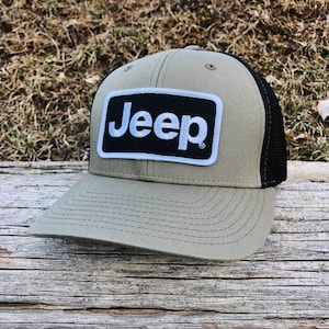Może przedstawiać: Czapka trucker w kolorze khaki i czarnym z naszywką z logo Jeep w kolorze czarnym i białym.