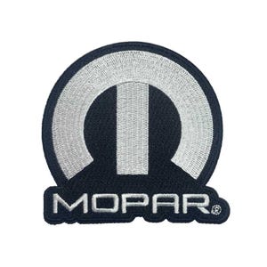 Puede incluir: Parche bordado en blanco y negro con el logotipo de Mopar. El logotipo presenta una letra "M" estilizada con un círculo a su alrededor. La palabra "MOPAR" está escrita debajo del logotipo.