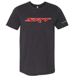May include: Dark grey t-shirt with the red and white "SRT" logo across the chest. The sleeve features the word "DODGE" in white. The shirt is made of a soft material.