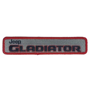Puede incluir: Parche bordado con la palabra "GLADIATOR" en letras azul oscuro, encima de la palabra "Jeep" en azul claro. El parche tiene un fondo gris y un borde rojo.