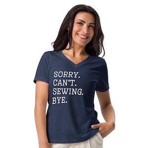 May include: A navy blue V-neck t-shirt with the text "SORRY. CAN'T. SEWING. BYE." in white. The shirt is made of a soft material.