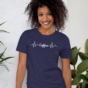 May include: A navy blue t-shirt with a white graphic of a heartbeat with the word "Coffee" inside.