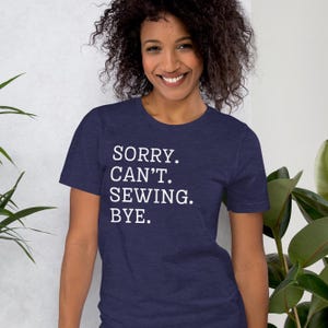 May include: A navy blue t-shirt with white text that reads "SORRY. CAN'T. SEWING. BYE."