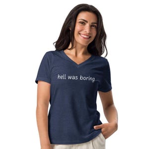 May include: A navy blue V-neck t-shirt with the phrase "hell was boring" printed in white. The shirt is made of a soft, comfortable material.