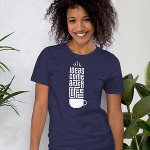 May include: Navy blue t-shirt with the text "IDEAS COME AFTER COFFEE" in a vertical design. The white text is stylized to resemble a coffee cup with steam rising from it. The shirt is made of a soft material.