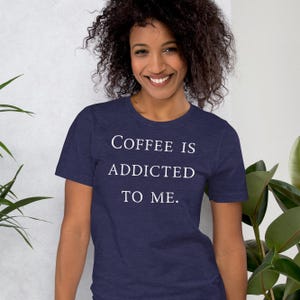 May include: A navy blue t-shirt with the text "COFFEE IS ADDICTED TO ME." printed in white.