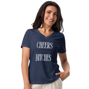 May include: A navy blue V-neck t-shirt with the words "CHEERS BITCHES" printed in white. The shirt is made of a soft material and is suitable for casual wear.