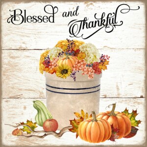 May include: A white ceramic crock filled with fall flowers and pumpkins, with the text "Blessed and Thankful" written in black script on a white wood background.