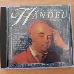 May include: A CD case featuring "The Masterpiece Collection: Handel Volume 5." The cover art displays a portrait of a man in a red coat and hat. The tracklist includes "Hallelujah Chorus" and "Water Music." The CD is a digital recording with 60+ minutes of music.