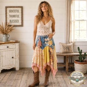 May include: A sleeveless cream-colored lace top with a V-neckline paired with a multi-patterned patchwork skirt featuring denim, floral prints, yellow fabric, and lace trim at the hem, worn with brown leather cowboy boots.