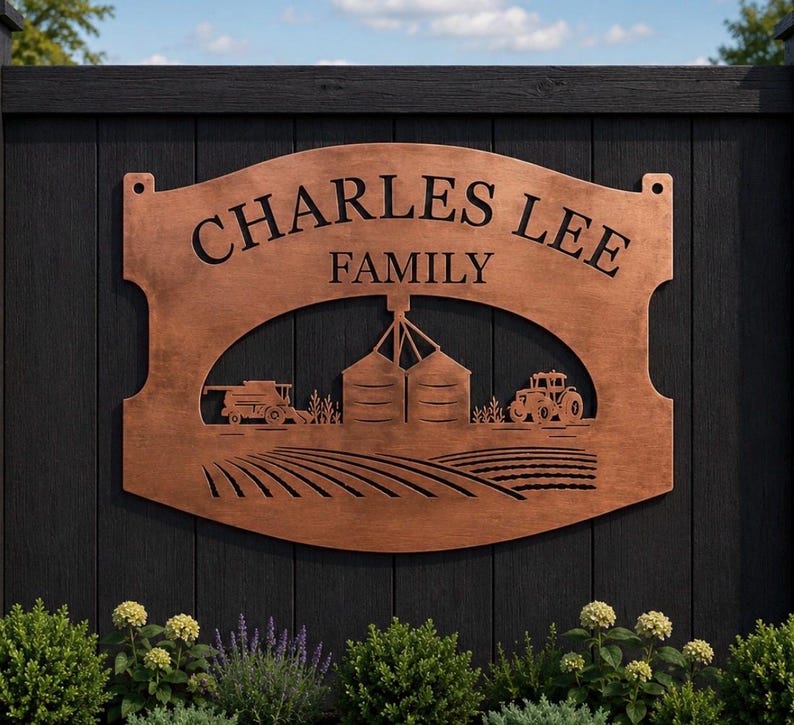 May include: A copper-colored metal sign with a curved top and bottom, featuring the text "CHARLES LEE FAMILY" in black lettering. The design includes a cutout illustration of a farm scene with two grain silos, a combine harvester, and a tractor.