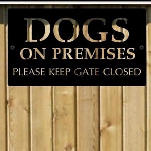 Pu&ograve; includere: Una targa rettangolare in metallo nero con scritte color oro metallizzato che recita DOGS ON PREMISES e PLEASE KEEP GATE CLOSED. La targa presenta due piccole viti nere, una nell'angolo superiore sinistro e una nell'angolo destro.