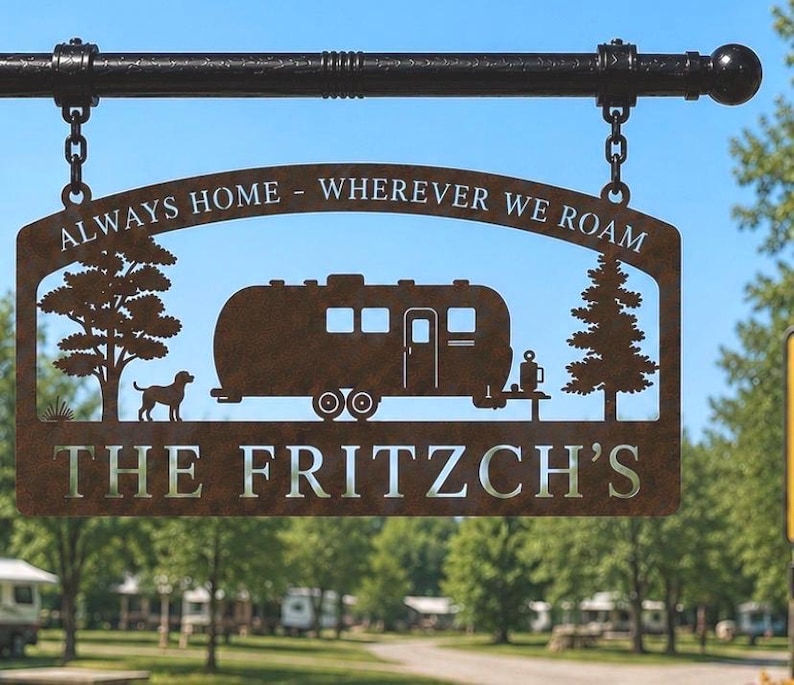 Puede incluir: Un letrero colgante de metal color &oacute;xido suspendido de una barra negra mediante dos cadenas. El letrero presenta un dise&ntilde;o recortado de una caravana, un perro y dos &aacute;rboles. El texto "ALWAYS HOME - WHEREVER WE ROAM" y "THE FRITZCH'S" est&aacute; recortado.