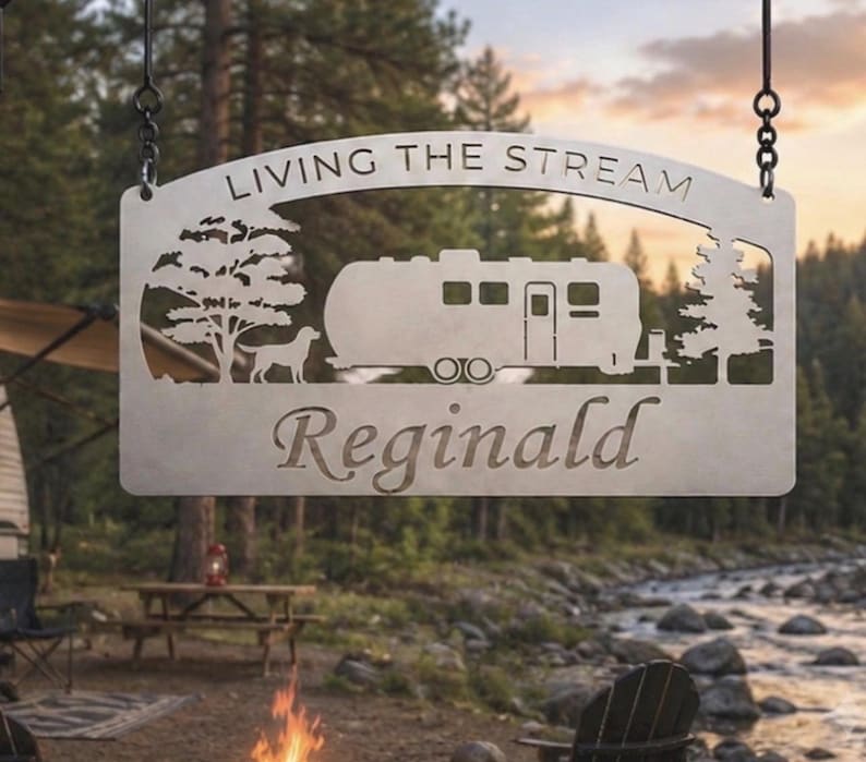 Puede incluir: Un letrero colgante de metal rectangular con un dise&ntilde;o cortado con l&aacute;ser de una caravana, un perro y dos &aacute;rboles. El texto "LIVING THE STREAM" est&aacute; arqueado en la parte superior y el nombre "Reginald" est&aacute; cortado en letra cursiva.