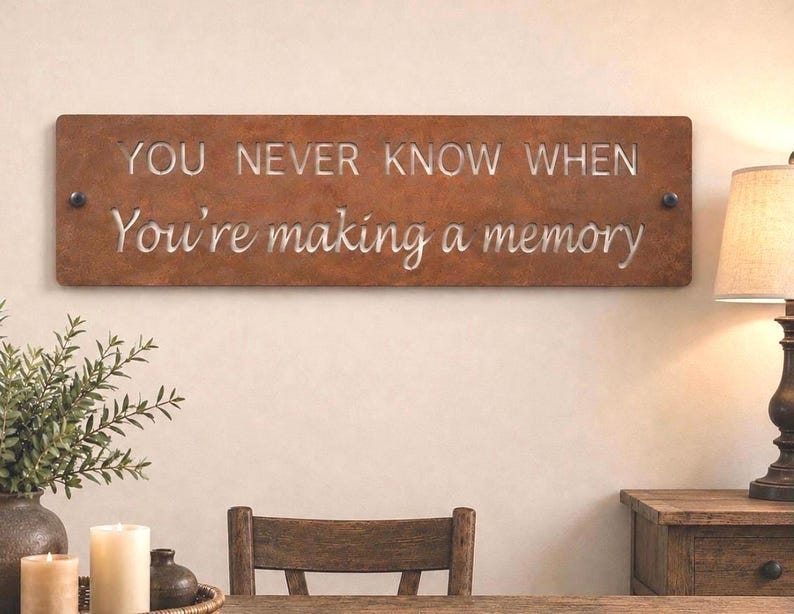 May include: A rectangular metal wall sign with a rusted brown finish featuring the cut-out text "YOU NEVER KNOW WHEN" in block letters and "You're making a memory" in a cursive script, secured by two dark circular fasteners on the left and right.
