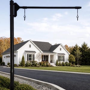 May include: A black metal sign post featuring a vertical pole and a horizontal arm extending outward. The arm includes two downward-facing hooks with circular loops at the ends, designed for hanging signage, positioned in front of a white house.