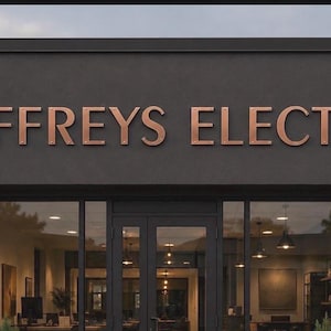 May include: A storefront exterior featuring a dark gray facade with the copper-colored text JEFFREYS ELECTRIC mounted above a glass entrance. Two black wall-mounted lamps flank the doorway, illuminating the interior office space visible through glass.