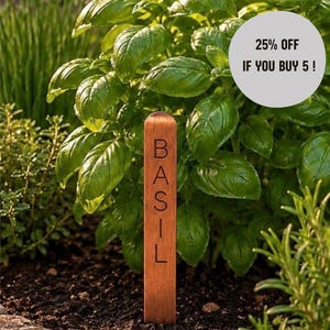 May include: A vertical brown wooden plant marker with the word BASIL engraved in black capital letters, positioned in dark soil in front of a green basil plant. A circular light grey graphic overlay displays the text 25% OFF IF YOU BUY 5!
