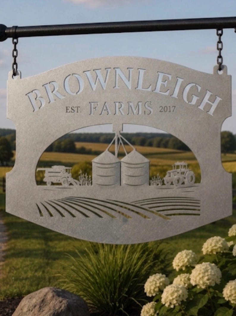 May include: A silver-colored metal hanging sign featuring the text "BROWNLEIGH FARMS EST. 2017" cut out from the top. The center displays a detailed silhouette of two grain silos, a tractor, and a combine harvester above a field of rows.