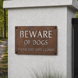 Può includere: Una targa rettangolare in metallo color ruggine montata su un pilastro bianco testurizzato. La targa presenta lettere ritagliate che recitano BEWARE OF DOGS e PLEASE KEEP GATE CLOSED. Quattro fissaggi circolari scuri fissano la targa.