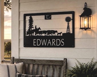 May include: A rectangular black metal wall sign featuring a cutout silhouette of a ranch scene with a person on horseback, cattle, a dog, a tall tree, and a windmill. The letter E and a slash are at the top, and the name EDWARDS is at the bottom.