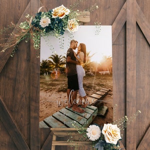 May include: A wedding welcome sign with a photo of a couple on a beach. The sign says "Welcome" with the couple's names and wedding date: June 26, 2021.