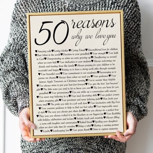 May include: A framed print with a gold frame and a white background. The print features a black and white design with the text "50 reasons why we love you" and a list of reasons written in black.