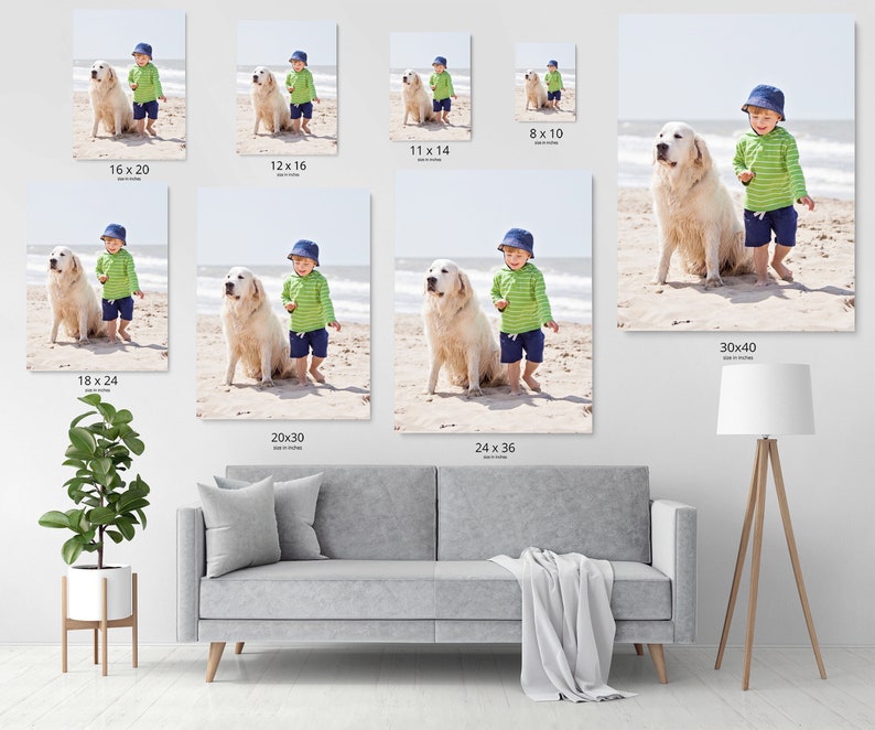 Op de afbeelding: Een jonge jongen in een groen-wit gestreept shirt en blauwe broek staat op een strand met een witte hond. De jongen draagt een blauwe pet en de hond kijkt naar de camera.