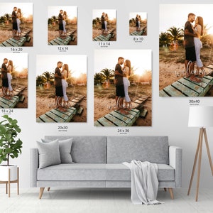 May include: A wedding welcome sign with a couple standing on a wooden dock. The sign says "Welcome" with the date "June 26, 2021" underneath. The couple is wearing white clothing and is standing in front of a sunset.